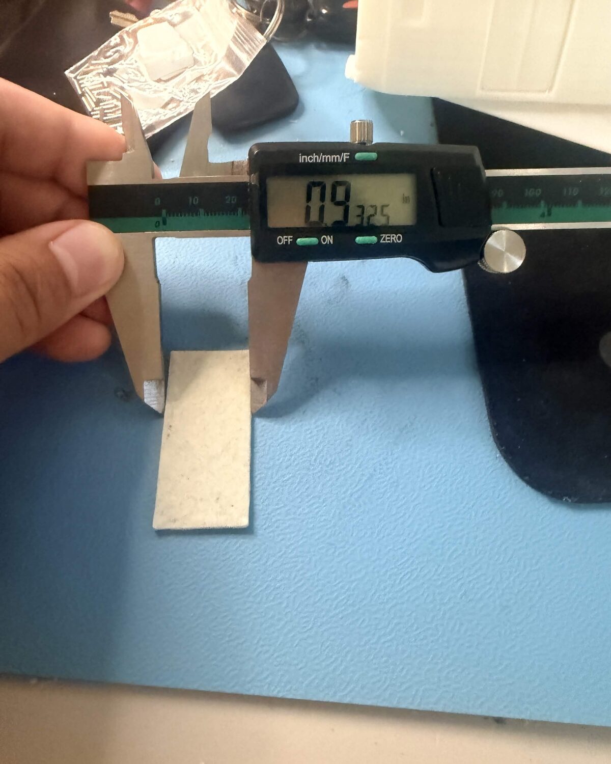 Digital calipers measuring a fired glass sample