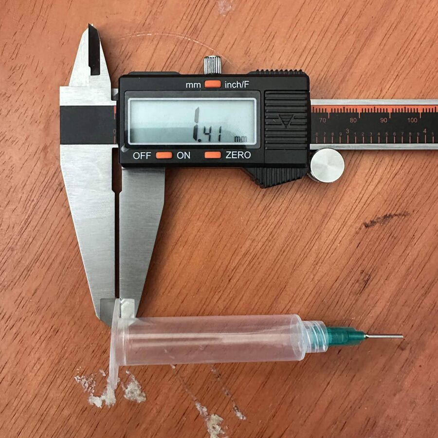 A syringe and needle measured with digital calipers